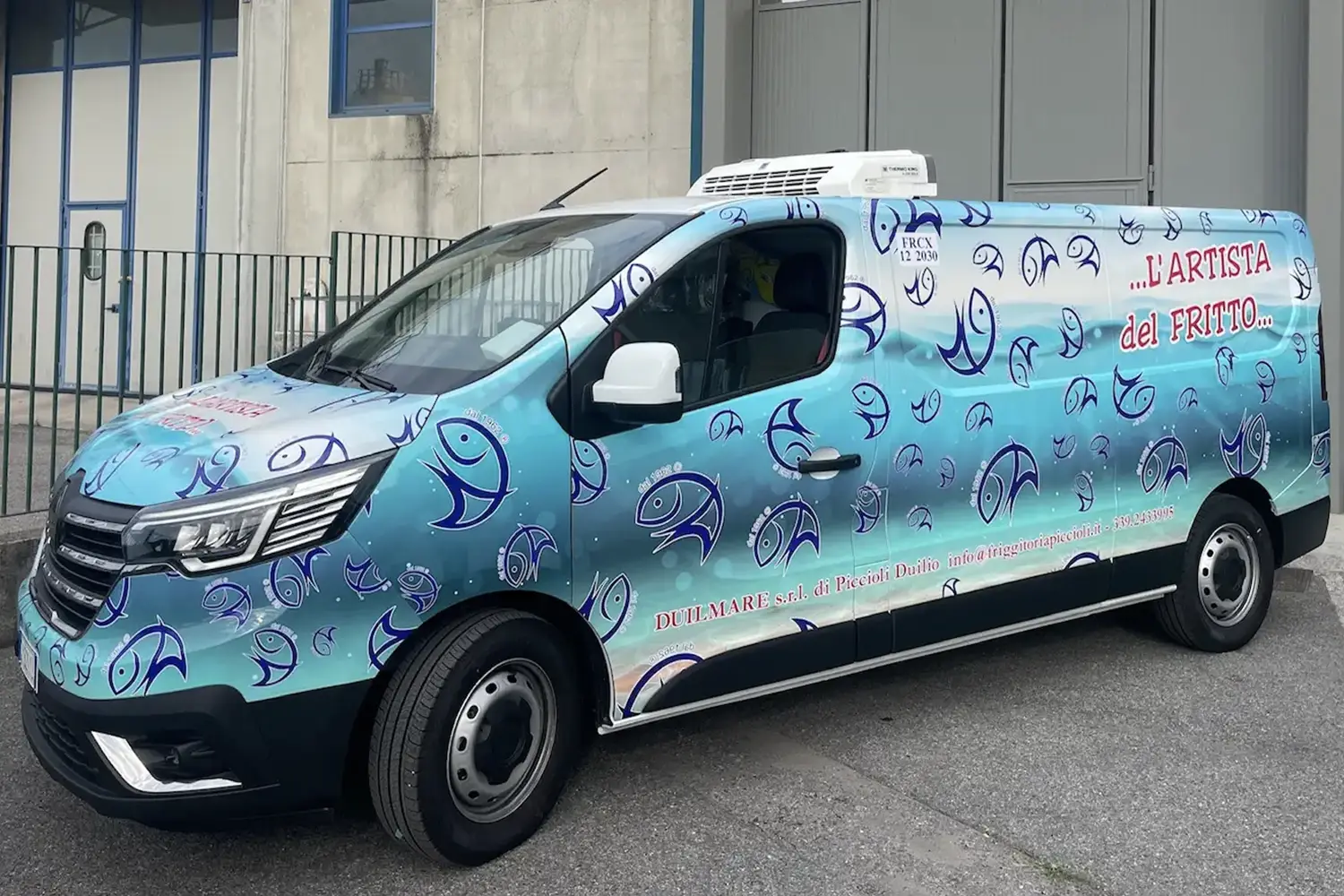 Furgone refrigerato con carrozzeria interamente rivestita da una grafica azzurra con illustrazioni di pesci e la scritta L'Artista del Fritto, appartenente all'azienda Duilmare srl di Piccioli Duilio.