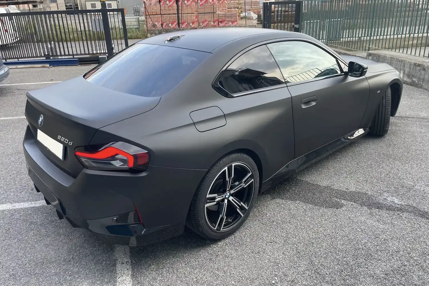 BMW Serie 2 Coupe interamente rivestita con pellicola nero opaco, cerchi in lega neri e dettagli fanali posteriori in rosso.